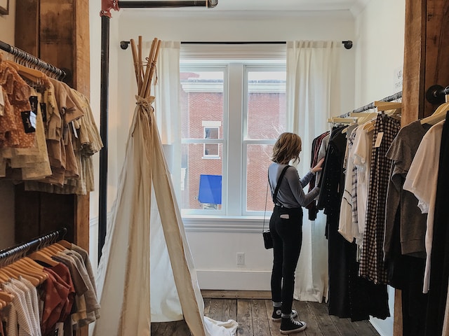 A woman browsing the collection of clothes displayed at a boutique.