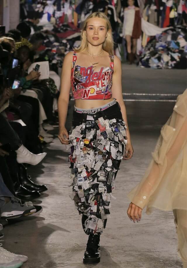 A model walks the runway with pants made from clothing tags.