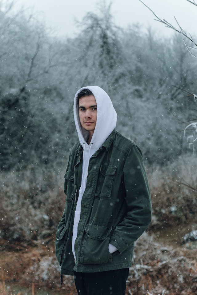 A guy with a hoodie and a jacket on in the snow