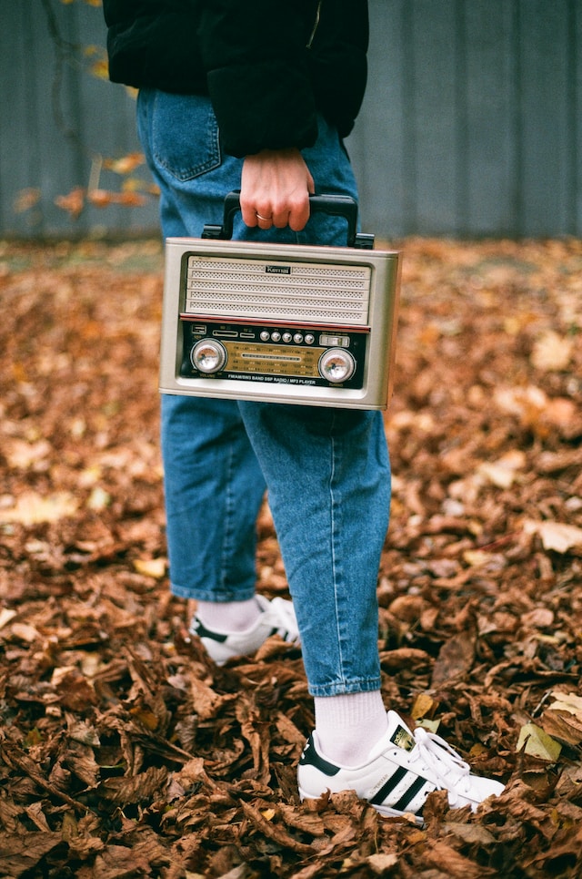 Person wearing a pair of jeans and carrying a vintage radio